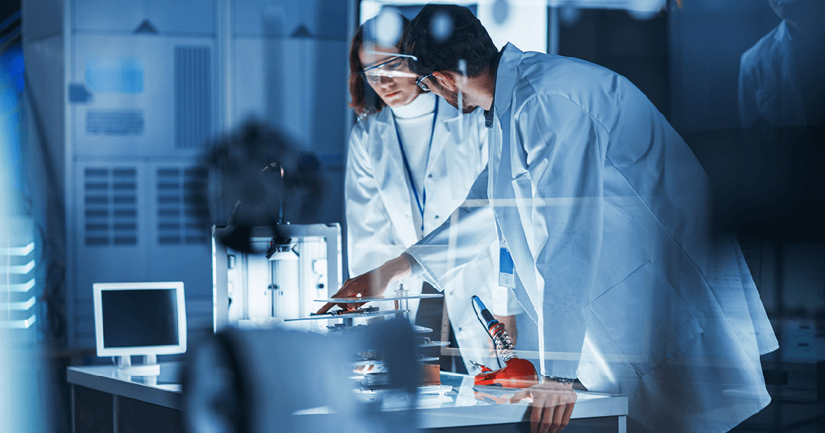 Two scientists in lab coats looking at a microscope.