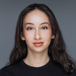 A woman with long dark hair, wearing a black top, faces the camera with a neutral expression against a gray background, representing Delta4's team.